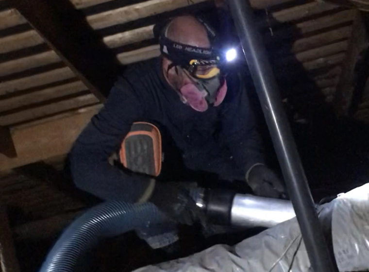 man spraying insulation material on an attic